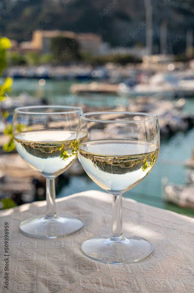 Two glasses of white wine from Cassis region served on outdoor terrace with view on old fisherman's harbour with colourful boats in Cassis, Provence, France