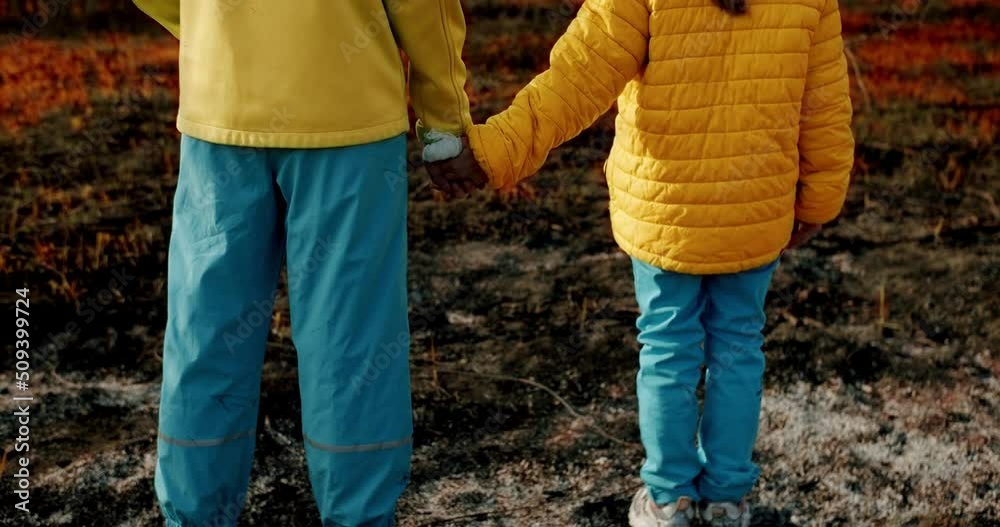 The little sisters dressed in the colors of the Ukrainian flag holding hands, on a background of earth burned during the war. Stop war in Ukraine.kid homeless. Russian aggression. Crisis, war conflict The little sisters dressed in the colors of the Ukrainian flag holding hands, on a background of earth burned during the war. Stop war in Ukraine.kid homeless. Russian aggression. Crisis, war conflict