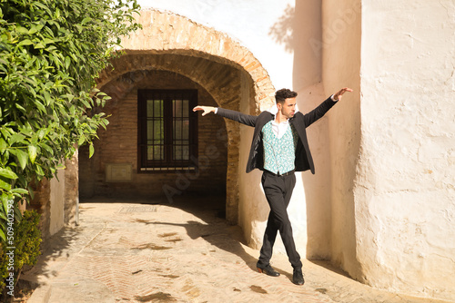 Young Spanish man with jacket, pants and black dancing shoes, white shirt and green vest, dancing flamenco in the street. Typical Spanish concept, art, dance, culture, tradition. © Manuel
