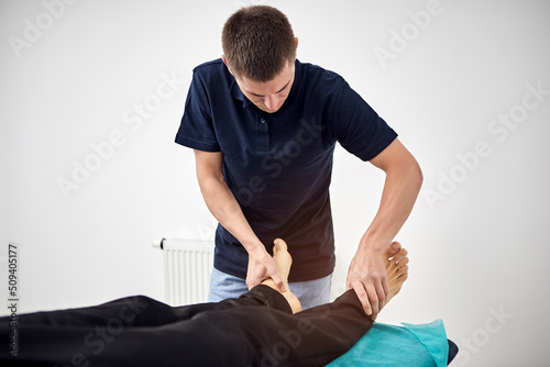 Physiotherapist massaging a male patient with an injured foot muscle. Treatment of sports injuries.