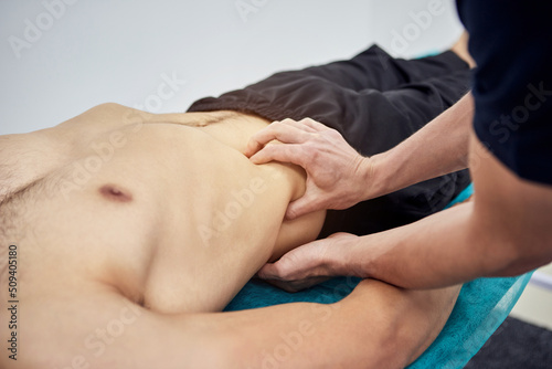 Physiotherapist massaging a male patient sportsman with damaged muscles in kinesio clinic. Treatment of sports injuries.