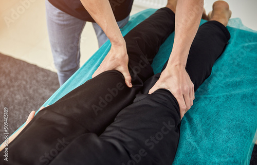 Physiotherapist massaging a male patient sportsman with damaged muscles in kinesio clinic. Treatment of sports injuries.