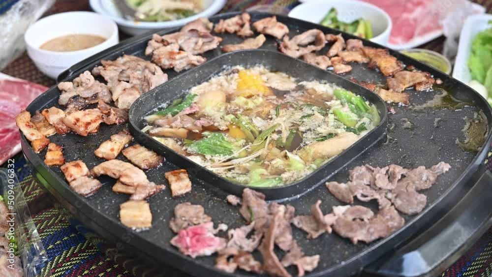 Close up of people enjoying their party with Korean BBQ and Shabu Shabu dinner. Korean BBQ is the popular method of grilling meat right at the dining table. Close up of people enjoying their party with Korean BBQ and Shabu Shabu dinner. Korean BBQ is the popular method of grilling meat right at the dining table.