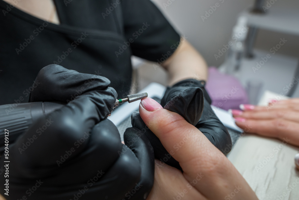 Manicurist removes gel polish from nails with a cutter. Hardware manicure close-up. Manicurist removes gel polish from nails with a cutter. Hardware manicure close-up.