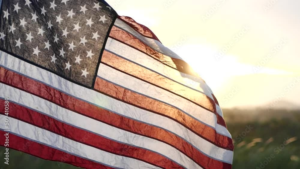 American USA flag waving in the wind against sunset in nature outdoor background. Concept of 4th of July, Memorial Day, Independence Day, Veterans Day, American Celebration, Patriots, Labor, President