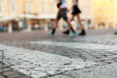 Stone pavement in perspective. Old street paved with stone blocks with white lines. Shallow depth of field. Vintage grunge texture. City       and people on background.