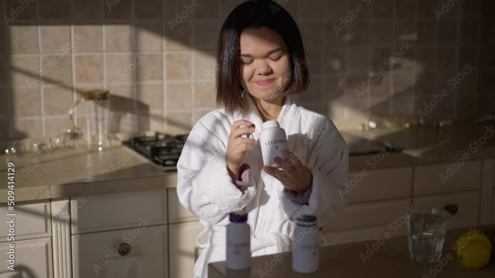Brunette positive little woman choosing vitamins standing on sunny kitchen at home. Portrait of smiling charming Caucasian little person with pharmaceutical drugs indoors in the morning Brunette positive little woman choosing vitamins standing on sunny kitchen at home. Portrait of smiling charming Caucasian little person with pharmaceutical drugs indoors in the morning