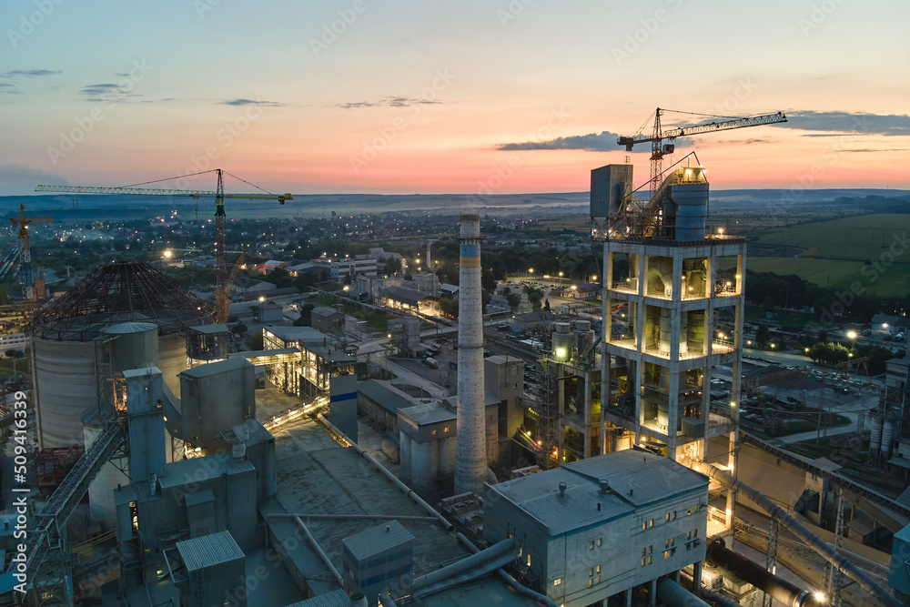 Aerial view of cement factory with high concrete plant structure and tower cranes at industrial production area at night. Manufacture and global industry concept Aerial view of cement factory with high concrete plant structure and tower cranes at industrial production area at night. Manufacture and global industry concept