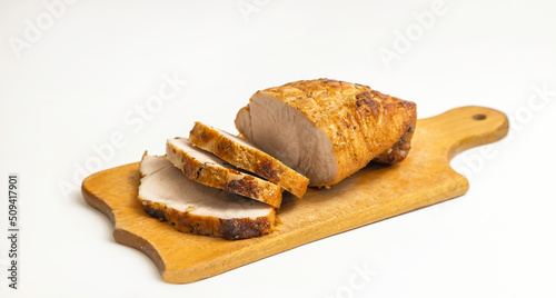 Homemade baked pork tenderloin with spices on a wooden kitchen board, on a white background