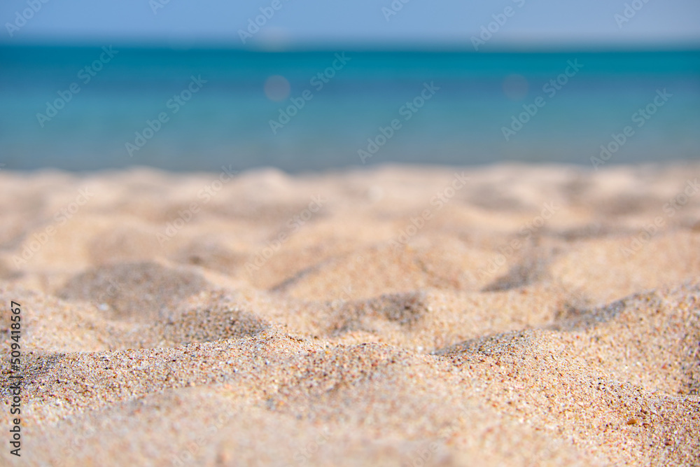 Close up of clean yellow sand surface covering seaside beach with blue sea water on background. Travel and vacations concept Close up of clean yellow sand surface covering seaside beach with blue sea water on background. Travel and vacations concept