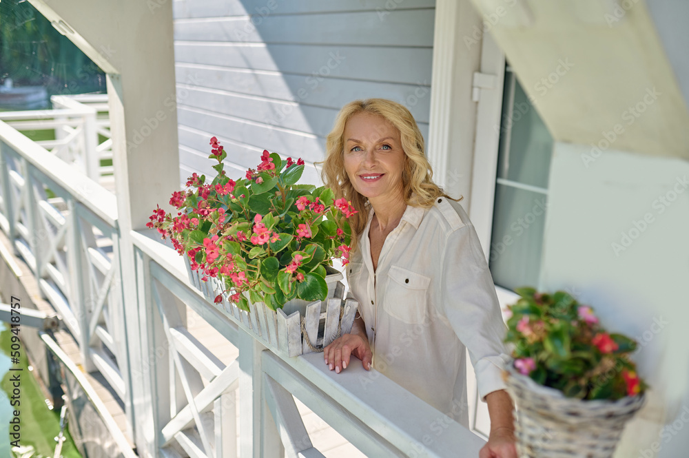 Pretty blonde woman in white with the flowers at her house