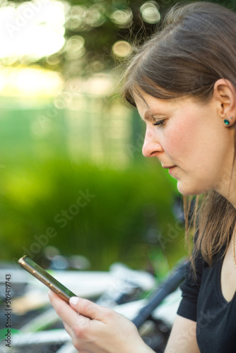 Young attractive woman looking at the phone. Portrait of young woman outdoor looking at mobile phone and smiling.