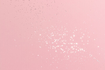 Sparkling silver glitter on pink background. Holiday blurred lights