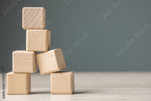Wooden cubes are built as a tower and risk falling down caused by the only one on the base is in the wrong composition, looking unstable and fragile. Weakest one in a teamwork
