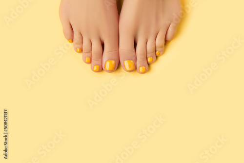 Womans feet with spring summer nail design on yellow background. Body treatment