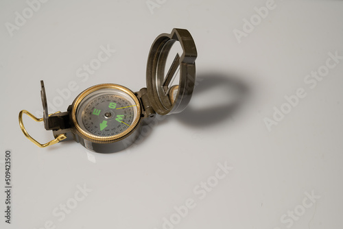 A magnetic compass with a heliograph lies on a white surface. There is free space for text. photo