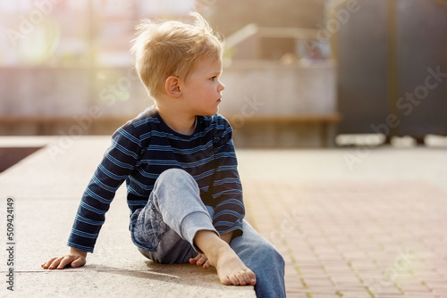 Little boy sitting by the fountain on a Sunny day, the child looks into the distance, there is free space for text in the picture