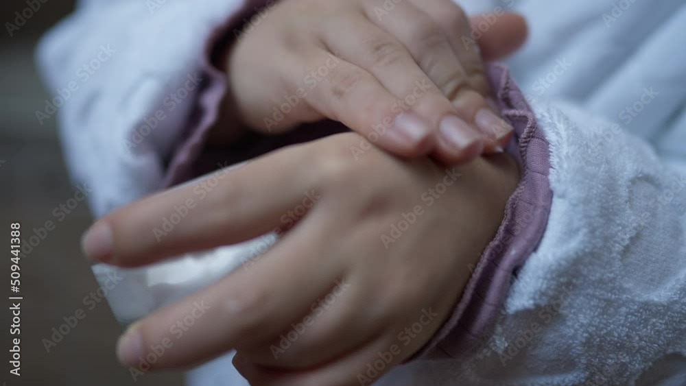 Close-up hands of little person applying moisturizer on palms. Unrecognizable Caucasian little woman in white bathrobe rubbing cream in skin Close-up hands of little person applying moisturizer on palms. Unrecognizable Caucasian little woman in white bathrobe rubbing cream in skin