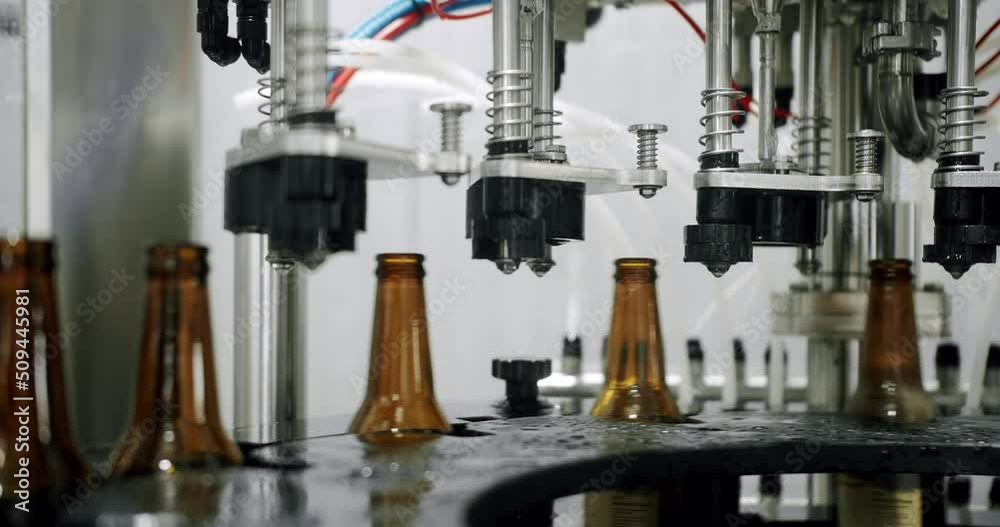Bottles of brown beer in a factory moving along the conveyor belt. Beer bottles are filled with automatic beer. Modern technology in a factory. Factory, beer concept. Bottles of brown beer in a factory moving along the conveyor belt. Beer bottles are filled with automatic beer. Modern technology in a factory. Factory, beer concept.