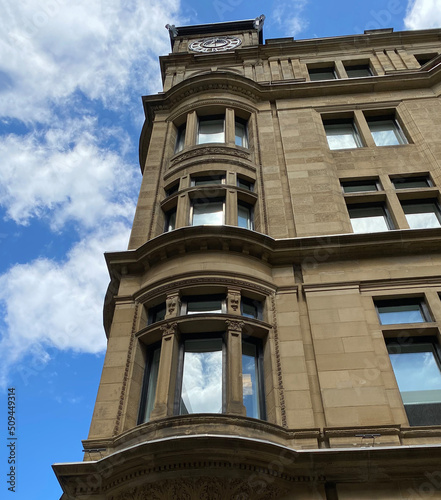 Façade d'un vieux bâtiment en pierres dont les fenêtres reflètent le ciel bleu dans le Vieux-Port de Montréal photo
