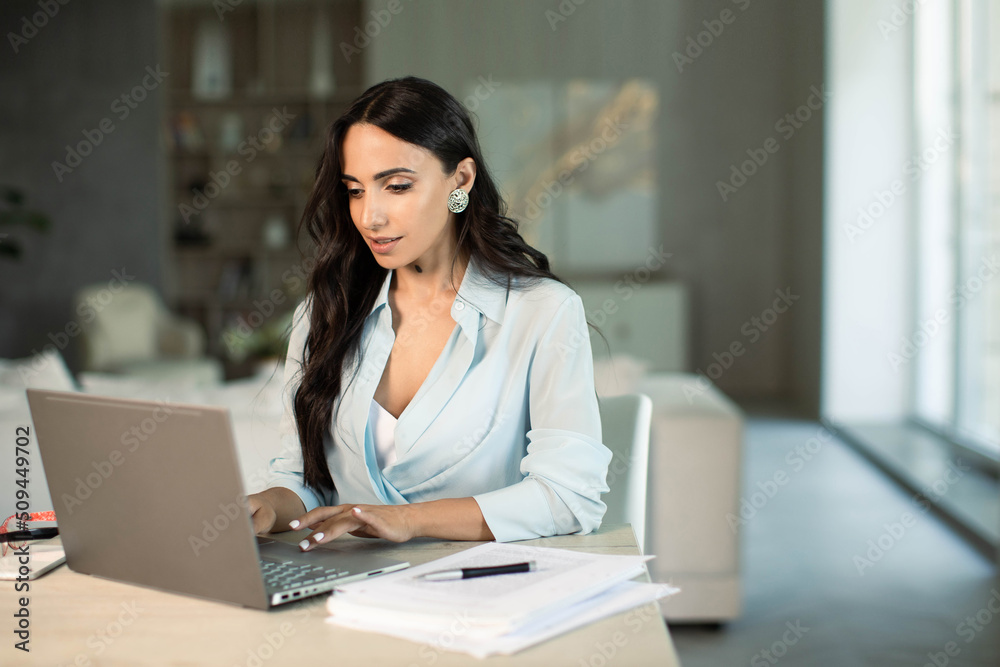 Smiling successful female using laptop computer indoors at home office, making notes on papers, remote work and small business freelancer, education and student,self employed Smiling successful female using laptop computer indoors at home office, making notes on papers, remote work and small business freelancer, education and student,self employed