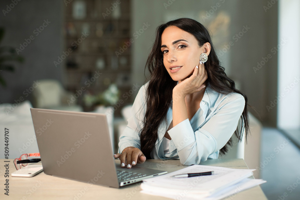 Smiling successful female using laptop computer indoors at home office, making notes on papers, remote work and small business freelancer, education and student, self employed Smiling successful female using laptop computer indoors at home office, making notes on papers, remote work and small business freelancer, education and student, self employed