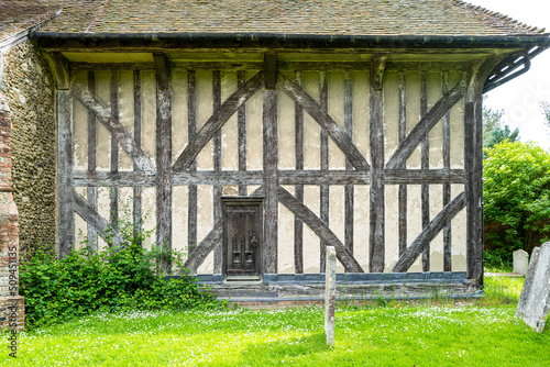 Fine exterior view of an old, Tudor built Church and its cemetery. The fine wooden beams and entrance to the belfry can be seen, one of the are wooden bell tower churches. photo