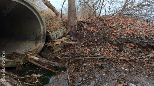 Concrete sewer pipe emptying onto rocky beach.