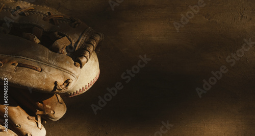 Old vintage sports game concept with baseball ball in glove on retro wood texture background with copy space on flat lay.