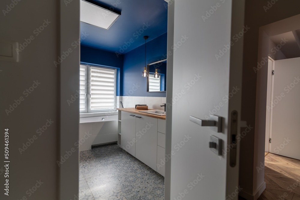 Entrance to the bathroom in a modern apartment. Bathroom door with blue walls and bathtub