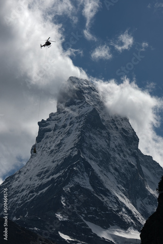 A picture of Matterhorn with cloud and helicopter passing by insight.The Matterhorn is a mountain of the Alps, straddling the main watershed and border between Switzerland and Italy.