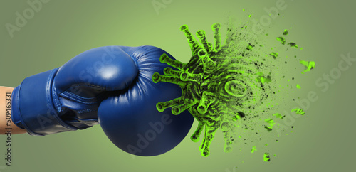Hand in boxing glove kicking cigarette on green background. Concept of immunity photo