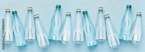 Many bottles of clean water on light blue background, top view photo