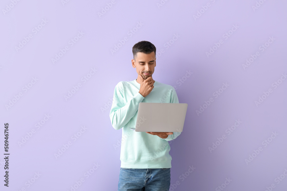 Thoughtful handsome man using laptop on lilac background Thoughtful handsome man using laptop on lilac background