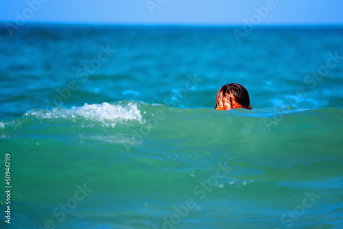 Portrait of young child girl on breaking wave. Kid in danger during sea swimming. Copy space for text. Horizontal image.