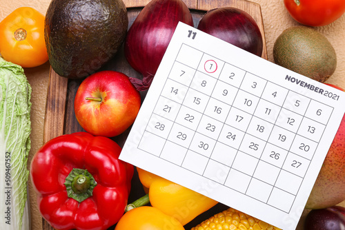 Fresh vegetables and calendar with marked date NOVEMBER 1 on color background, closeup. World Vegan Day concept