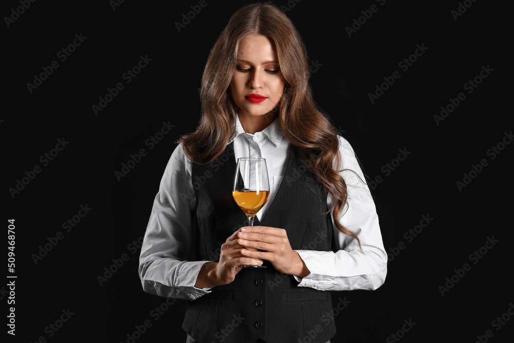 Beautiful female sommelier with wine on black background