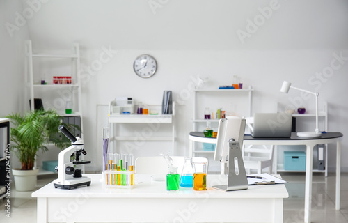 Microscope, tablet computer and chemical glassware on table in medical laboratory © Pixel-Shot