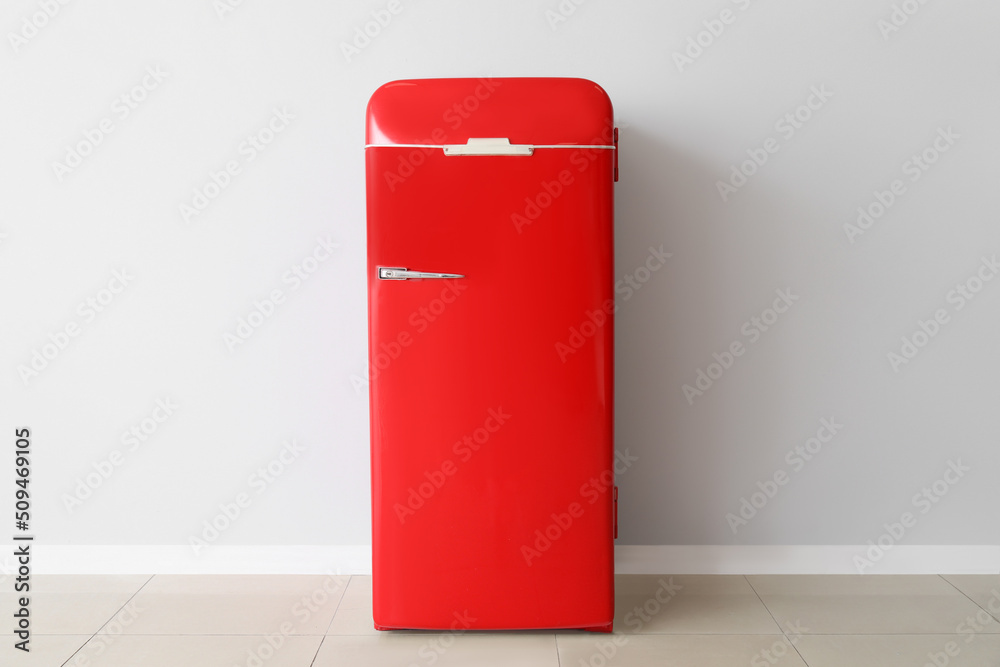 Stylish retro fridge near light wall in room