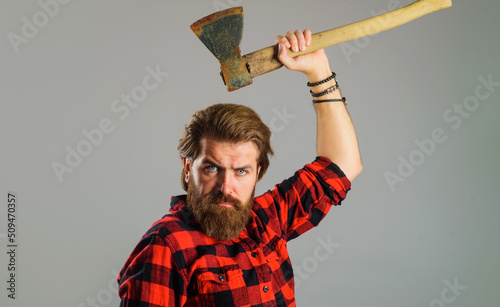 Canadian lumberjack in plaid shirt with axe. Logger tools. Bearded man with hatchet. Cutting wood.
