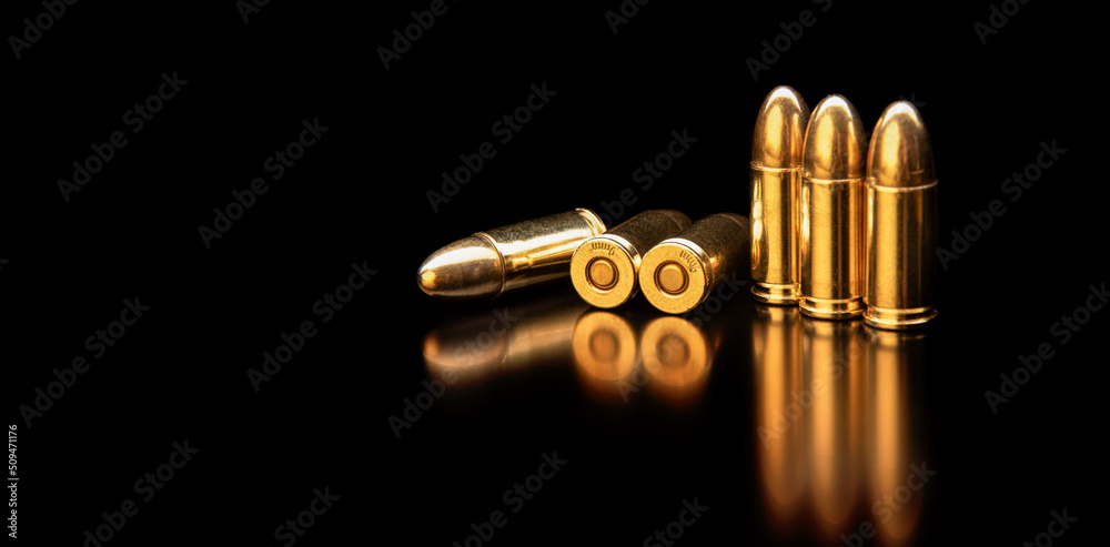 Pistol cartridges 9 mm on a smooth glossy surface with reflections. Ammunition for pistols and PCC carbines on a dark back. Pistol cartridges 9 mm on a smooth glossy surface with reflections. Ammunition for pistols and PCC carbines on a dark back.