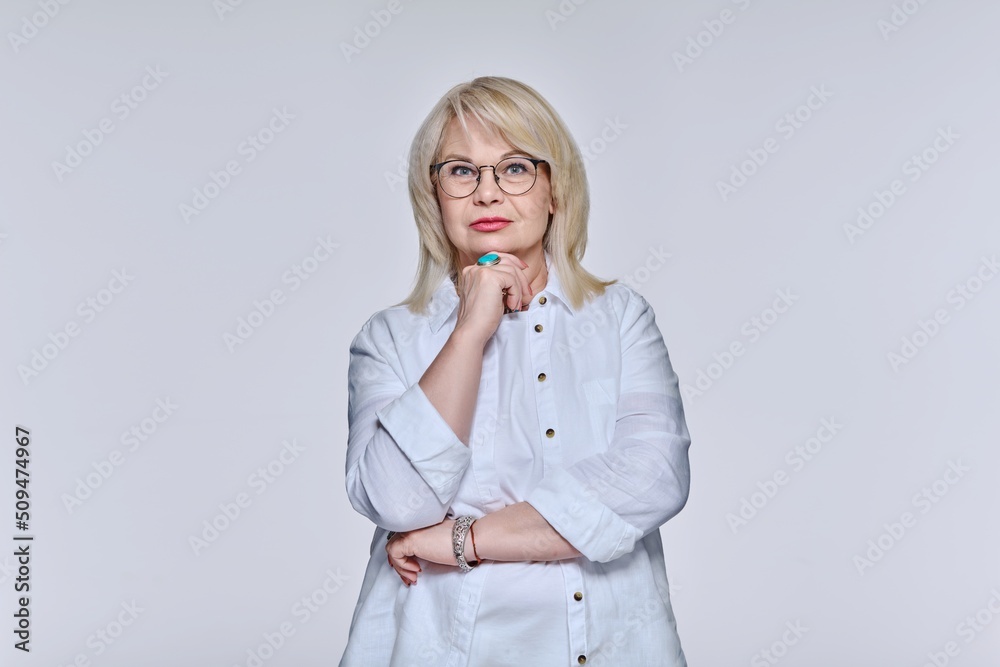 Portrait of mature woman in glasses looking at camera on light background Portrait of mature woman in glasses looking at camera on light background