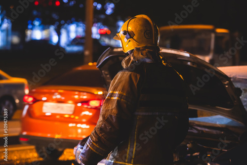Group of fire men in uniform during fire fighting operation in the night city streets, firefighters with the fire engine truck fighting vehicle in the background, emergency and rescue