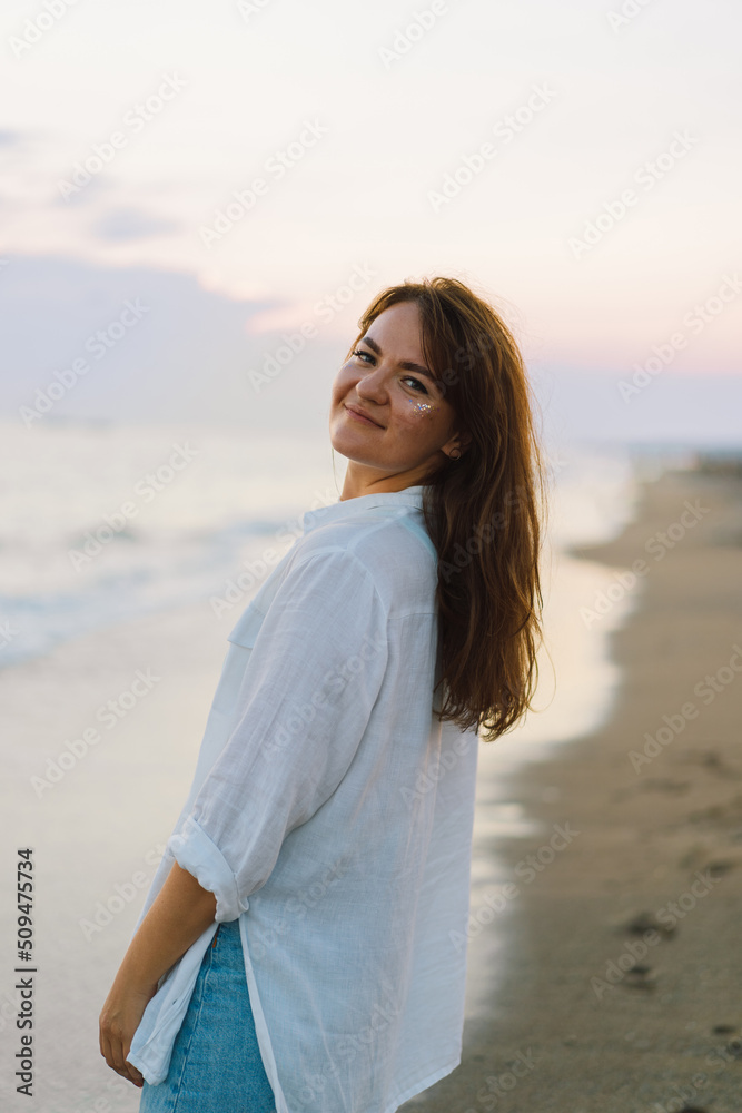 Portrait of a happy young woman on a background of beautiful sea. The girl looks at the magical sea. Freedom and happiness Portrait of a happy young woman on a background of beautiful sea. The girl looks at the magical sea. Freedom and happiness