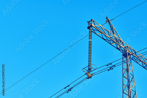 High voltage electricity tower with power line against blue sky. Overhead electric power line with insulators. Electricity generation, transmission, and distribution network. Indastry landscape. photo