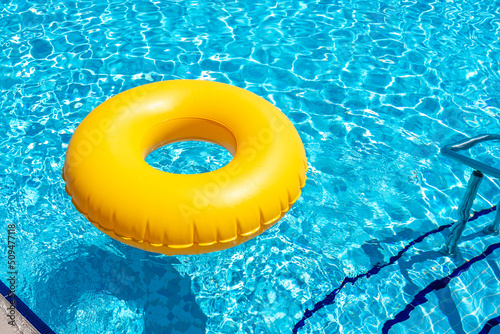 Yellow inflatable ring floating in swimming pool. Vacation concept with copy space