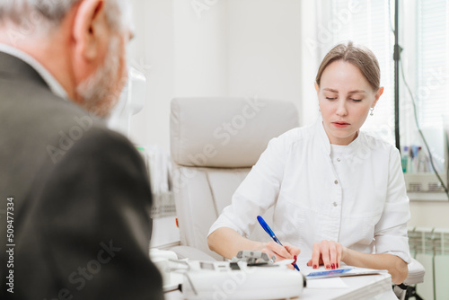 doctor interviews elderly man before being examined in ophthalmologist's office. © andrey