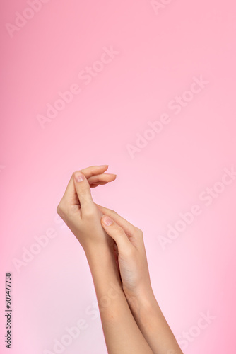 Women's hands are on pink background. Female hands use cosmetic cream. Hydrating and moisture soft face or hand cream - skin and body care concept.