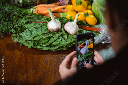 a person taking phone photos of a pile of vegetables (ID: 509480950)