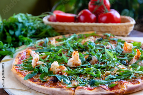 Delicious rustic Italian pizza with grilled Adriatic shrimps, mozzarella, sun dried tomatoes, arugula and parmesan cheese